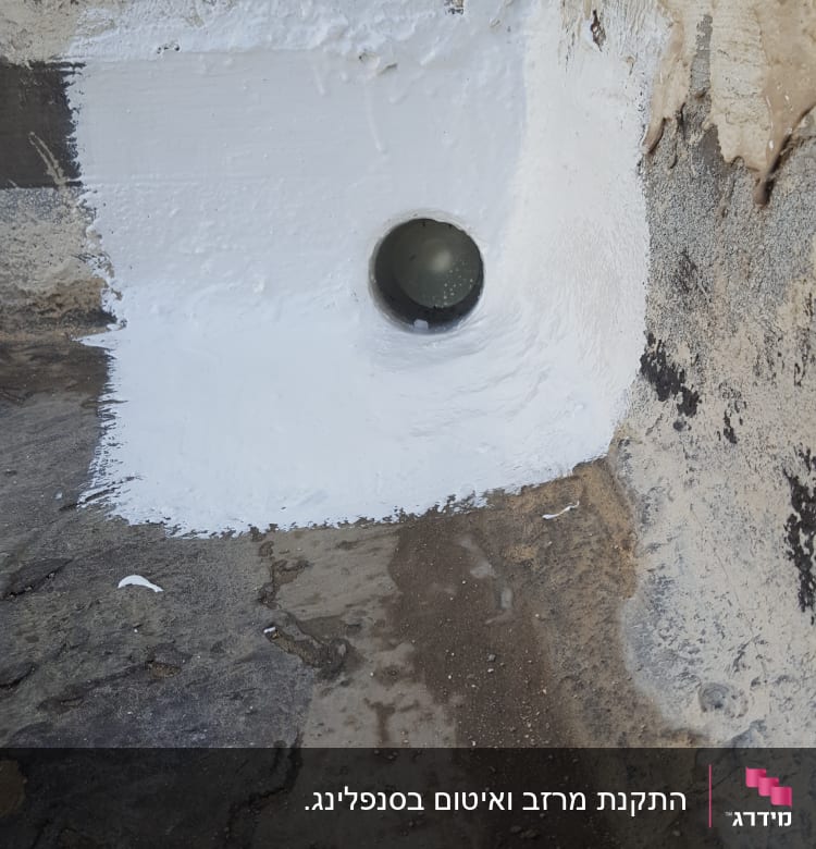 צינור מתכת בקיר עם איטום לבן סביבו